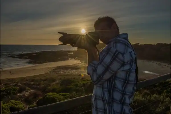 Man taking a photograph at sunset on Maui. 