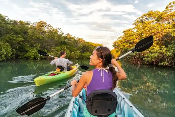 Two people kayaking down a river.